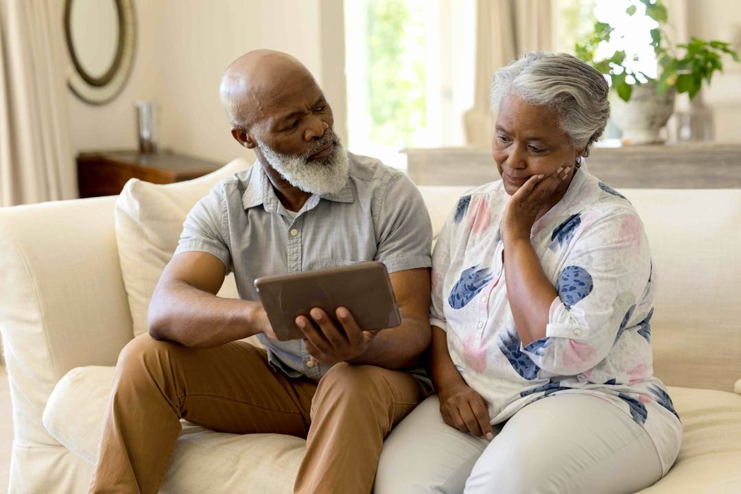 Older couple looking thoughtfully at a tablet screen
